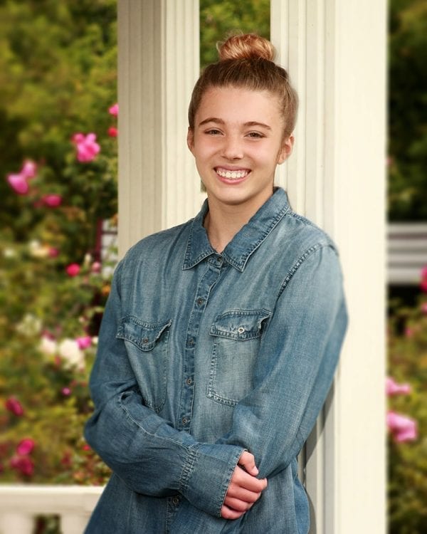 Portrait of a teen girl leaning against a post in a jean jacket