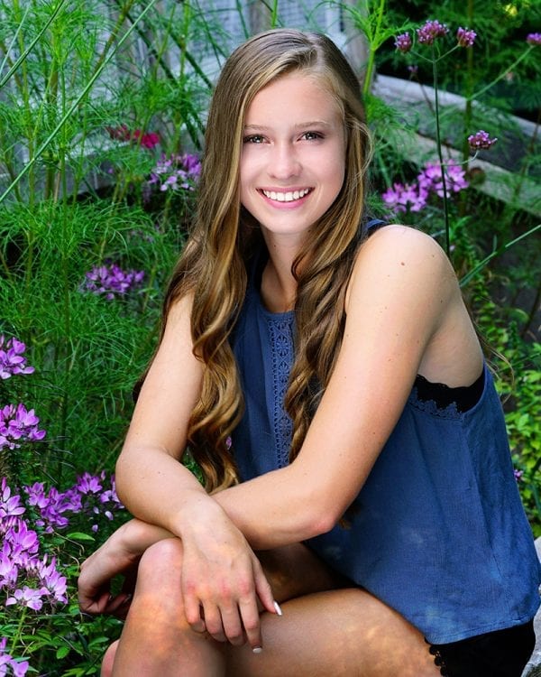 Portrait of a teen girl with a blue top and black shorts in natural setting