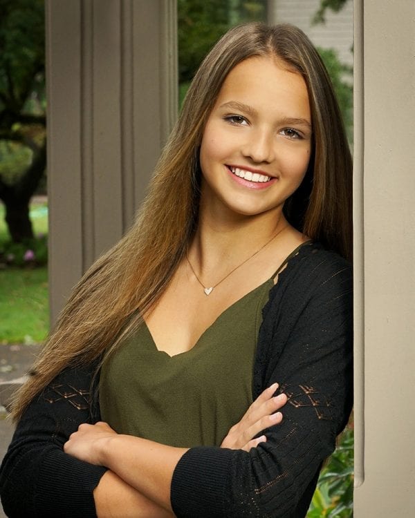 Portrait of a teen girl leaning against a wall in a nice outfit