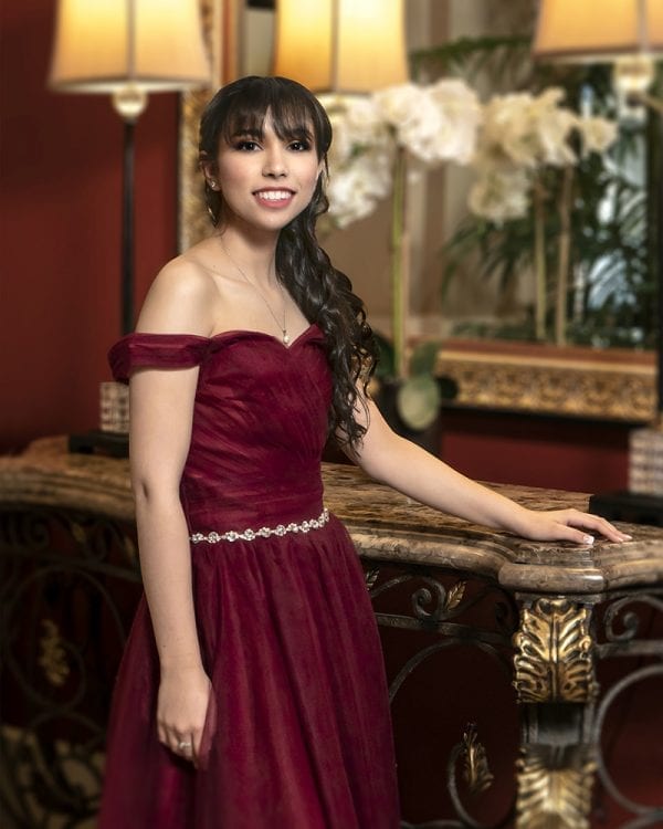 Portrait of a teen girl with an elegant dark red dress in an elegant setting