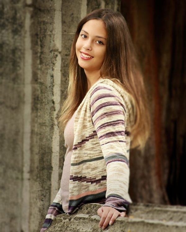 Portrait of a teen girl with her hand on a roman column that has fallen over