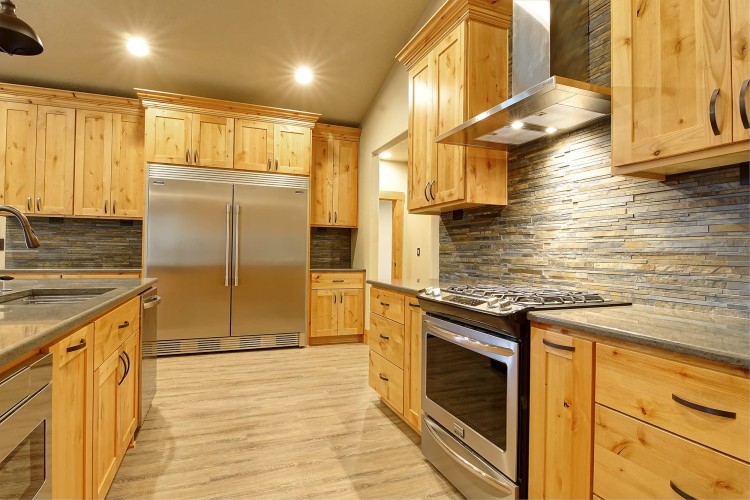 Newly refurbished kitchen with light wood cabinets and gray marble countertops