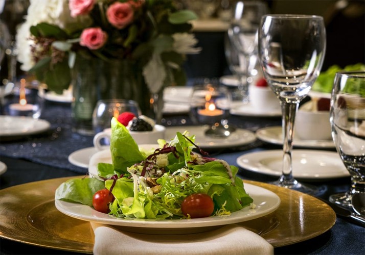 Salad plate on a gold accent plate with a whole table filled with fancy dishes and glasses