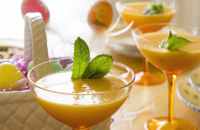 Mimosas each with a sprig of mint and an Easter basket in the background