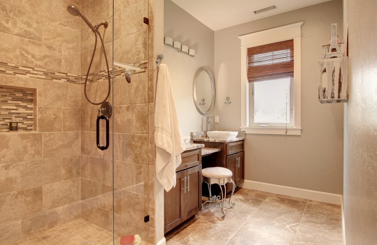 Light colored bathroom with walk in shower and two sinks