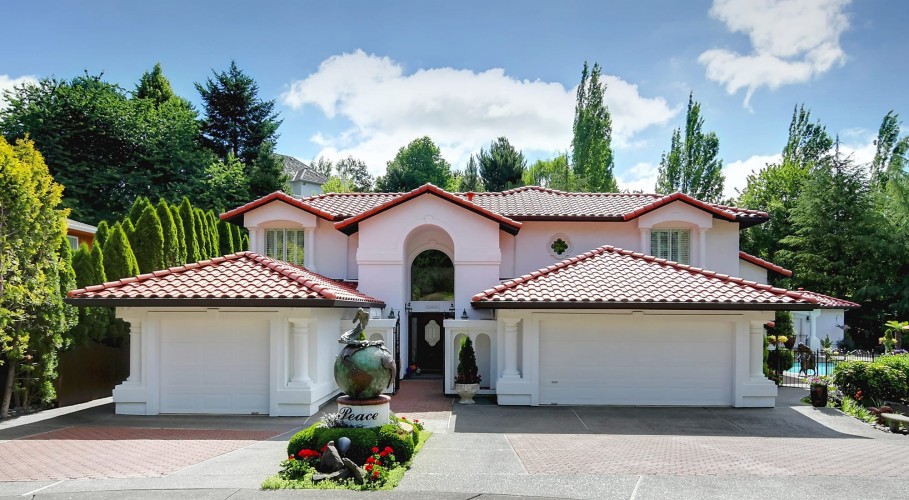 Exterior of a house painted white with red terra cotta roofing and an outdoor pool