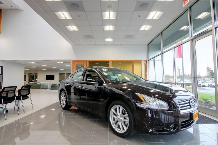 A black four door sedan displayed inside of a car dealership lobby