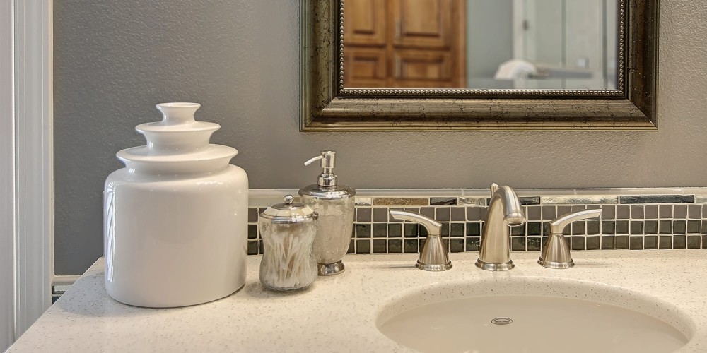 Light colored bathroom sink space with silver metallic accents