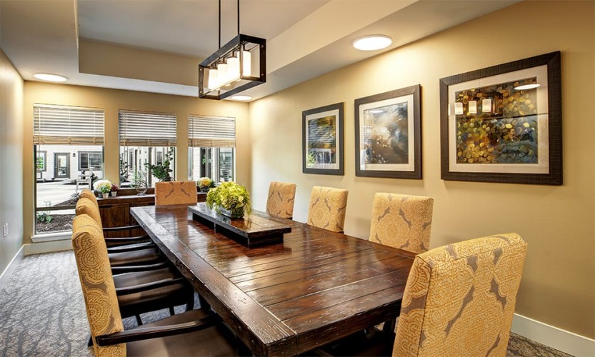 Formal dining room area with yellow and brown accent colors and a rustic yet elegant wood table