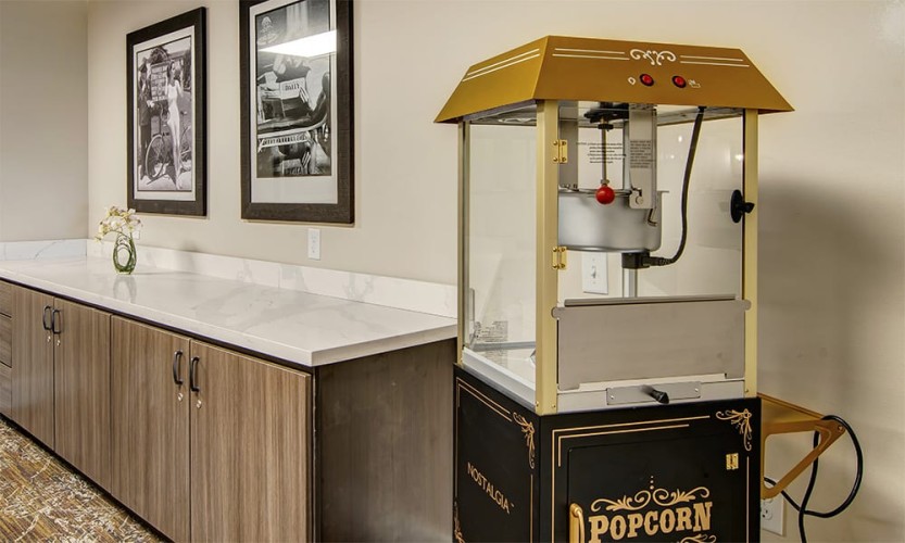 Movie theater popcorn maker next to a counter and photos of famous people on the walls
