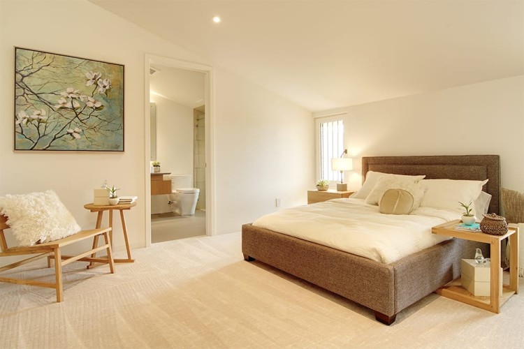 Light bedroom with a white bed, carpet, and walls and light wood furnishings