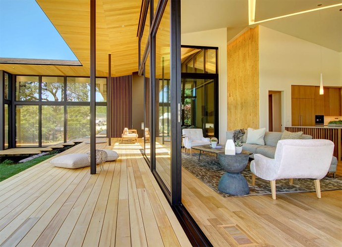 Sliding glass doors in the middle with the living room on the right and the deck on the left. Natural light wood floors and floor to ceiling windows