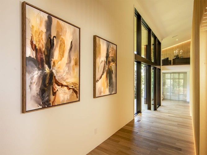 Hallway with abstract paintings and wood flooring