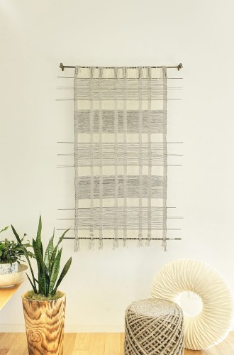 Light gray hanging weave art on a wall with other light accents