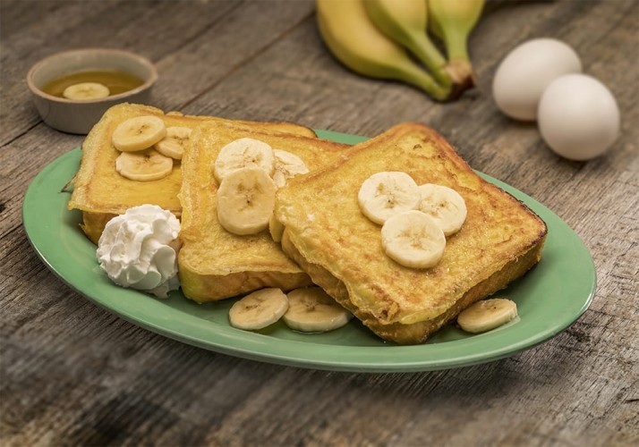 Syrupy french toast plate with banana slices and whipped cream