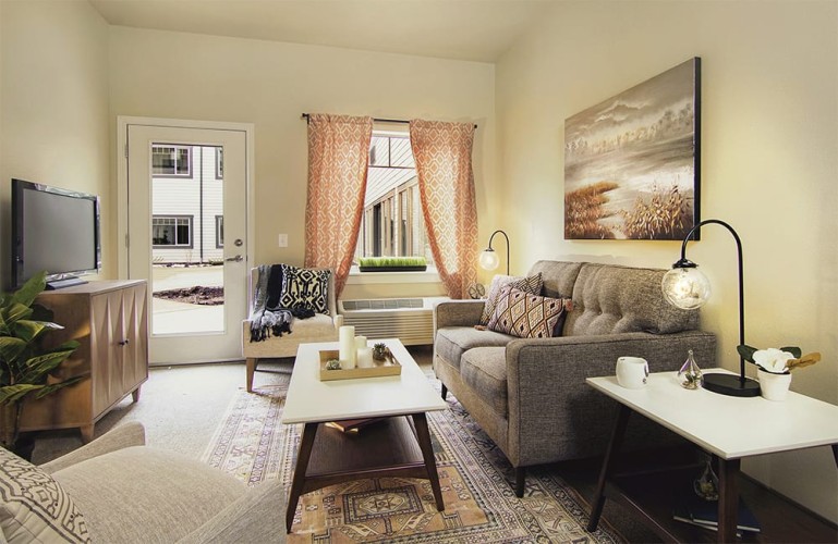 Small living room space with orange, gray, and black accent colors facing the windows