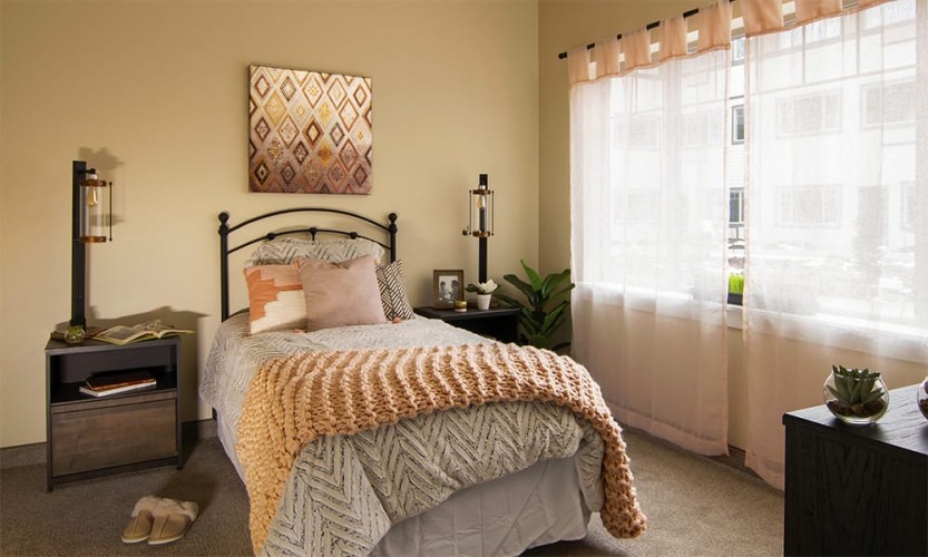 Small bedroom with light orange, gray, and black accent colors