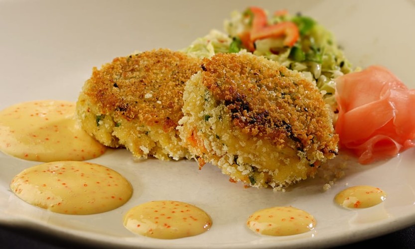 Close up of crab puffs plated with artistic sauce and salad
