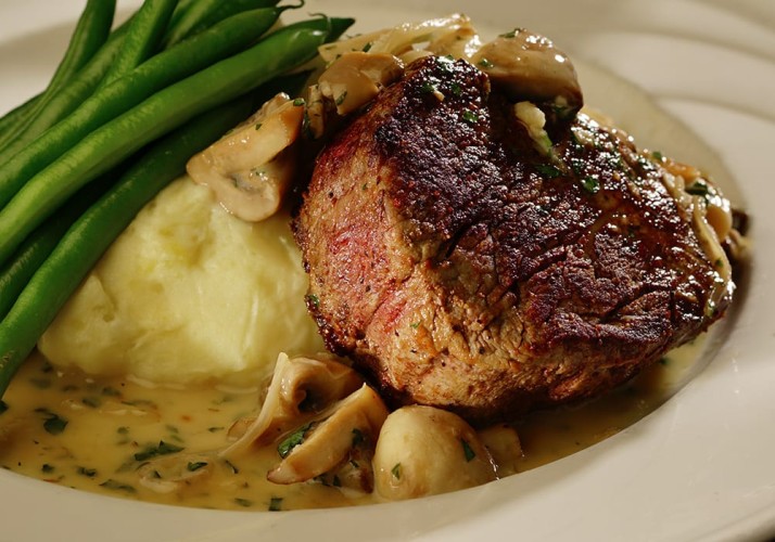 Closeup of juicy steak plate with mashed potatoes and string beans