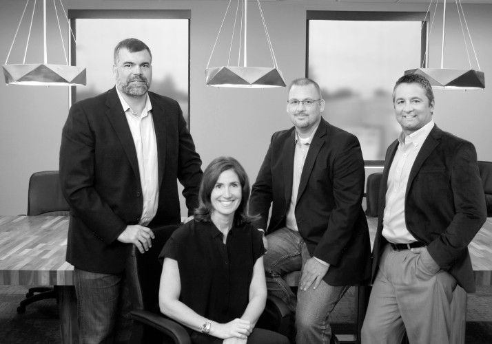 Black and white portrait of four business people smiling in a conference room